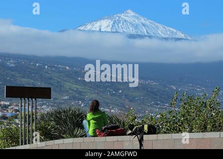 Young woman looks from the Mirador de Humbold at the snowy Teide volcano in Tenerife and over the Orotava valley Stock Photo