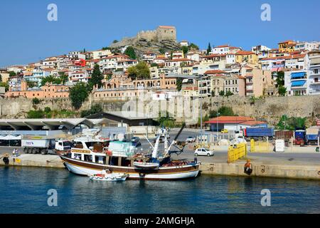 Kavala, Greece - September 18th 2015: Fishing ship and cars at ferry terminal in the harbor of the city in Eastmacedonia with Imaret hotel and medieva Stock Photo