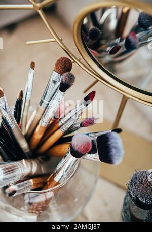 Many different makeup brushes in artist's studio with mirror reflection Stock Photo