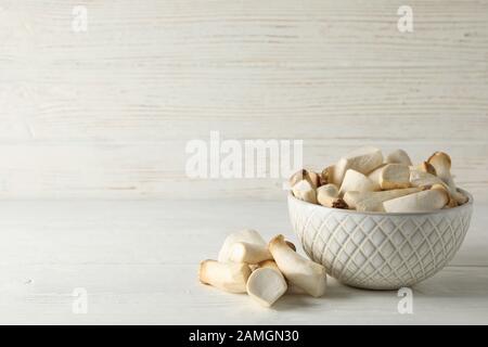 Fresh eringi mushrooms in bowl on white wood background, space for text Stock Photo