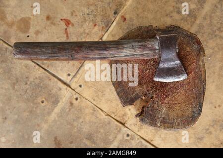 Chopping axe and Meat cleaver on wooden background . Ax stuck in a log near cauldron standing on a bonfire . Chopping board block and Meat cleaver Stock Photo