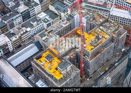 Construction site with cranes among other urban other houses. Construction workers are building. Aerial view. Top view. Stock Photo