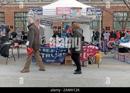 A couple of Trump supporters walk by one of many merchandise stands set up next to the line leading to a Trump Reelection Rally in Toledo, Ohio. Stock Photo