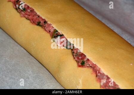 roll of swabian ravioli with fresh meat and green spinach leaf, homemade raw meat dumplings roll Stock Photo