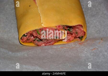 homemade raw meat dumplings roll close-up view, roll of swabian ravioli with fresh meat and green spinach leaf macro shot Stock Photo
