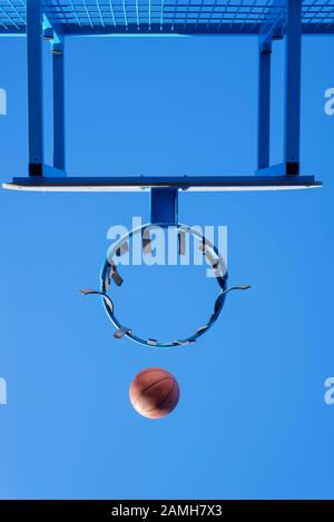 image of a ball beside a basketball hoop, basket against blue sky. Outdoor basketball court Stock Photo