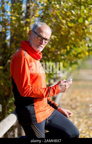 Senior runner in nature with smartphone. Stock Photo