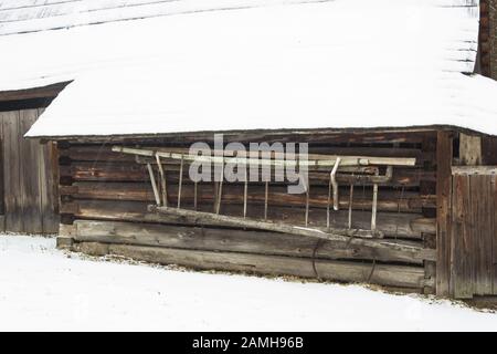 Retro old wooden ladder on log cabin in winter. Stock Photo