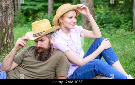 Choose proper clothing and equipment to hike and forest picnic. Reasons you should definitely wear more hats. Couple in straw hats sit meadow relaxing. Wearing sun hats protect head and hair from sun. Stock Photo