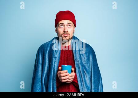 Boy caught a cold and drinks hot the. Cyan background. Concept of illness Stock Photo