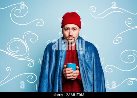 Boy caught a cold and drinks hot the. Cyan background. Concept of illness Stock Photo