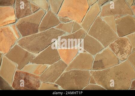 The light texture of stone wall, background. Facing with granite stones in chopped up shapes. The fragment of a new decorative stone laying Stock Photo