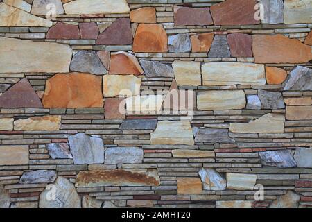 Multy-colored (colorful) decorative stone wall, texture, background. Varicolored natural stones in the wall construction Stock Photo