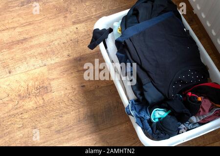 clothes in a full laundry basket on a laminaat floor, top view Stock Photo