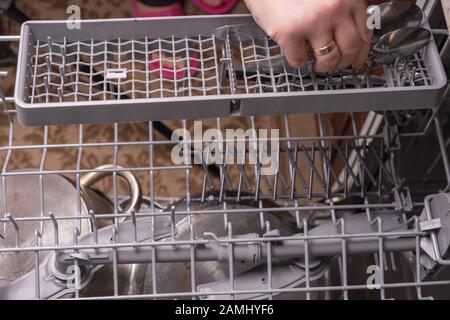 Loading dishes in the dishwasher, gray mesh dishwasher. Selective focus Stock Photo