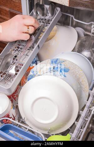 Loading dishes in the dishwasher, gray mesh dishwasher. Selective focus Stock Photo