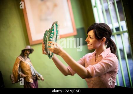 A woman thoughtfully looks at a decorative piece. Stock Photo