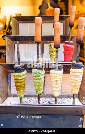 Cooking Trdelnik, a traditional cone-shaped puff pastry snack cooked on a wooden cone and filled with cream, sugar and nuts, Prague, Czech Republic Stock Photo