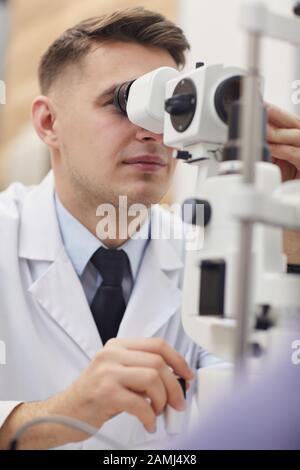 Close up portrait of male optometrist using refractometer machine while testing vision Stock Photo