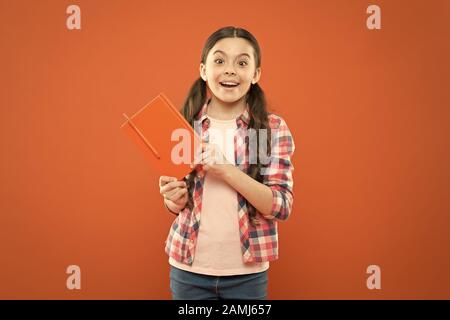 Pupil with work book. Literature and writing lesson. Schoolgirl with notebook doing homework. Learning language. Studying is exciting. Girl cute kid study with book. Interesting book. Did you know. Stock Photo