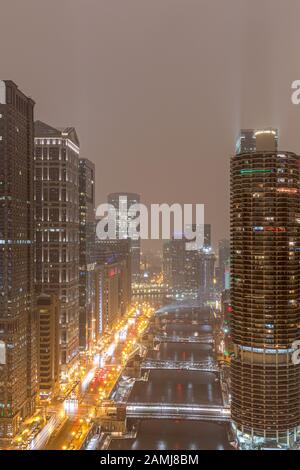 View of Chicago at night on a foggy evening, looking west along the Chicago River and West Wacker Drive.  Copy space in sky if needed. Stock Photo