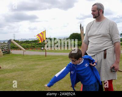 A young boy learning to throw an axe at a living history event Stock Photo