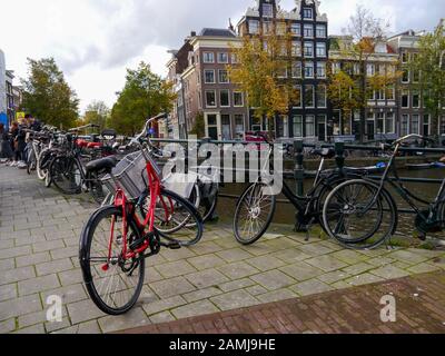 A bridge over a canal in the city of Amsterdam with bicycles chained to the railings. Stock Photo