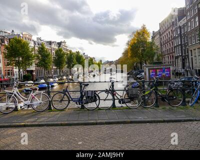 A bridge over a canal in the city of Amsterdam with bicycles chained to the railings. Stock Photo