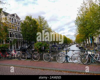 A bridge over a canal in the city of Amsterdam with bicycles chained to the railings. Stock Photo