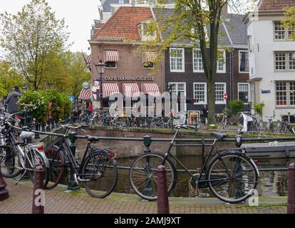 A bridge over a canal in the city of Amsterdam with bicycles chained to the railings. Stock Photo