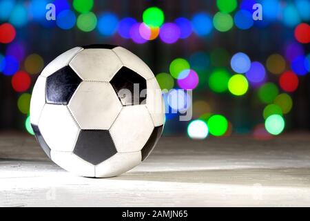 Football soccer on a white texture surface with a hard shadow on a colourful bokeh of lights on December. Stock Photo