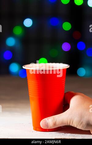 Hand holding a one use cup with lights on the background Stock Photo