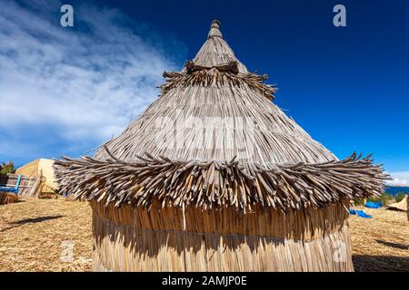 Traditional reed houses on floating Uros islands, at a distance, clouds, on Lake Titicaca in Peru, South America.