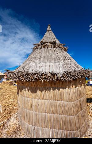 Traditional reed houses on floating Uros islands, at a distance, clouds, on Lake Titicaca in Peru, South America. Close-up. Stock Photo