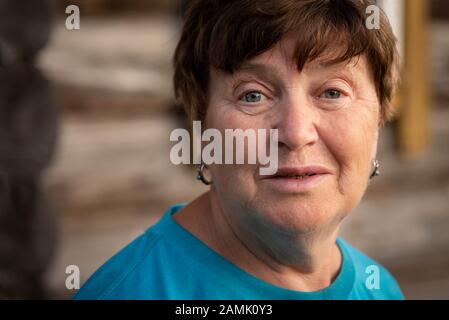 Close up portrait of a blue eyed senior Russian woman wearing a blue shirt. Stock Photo