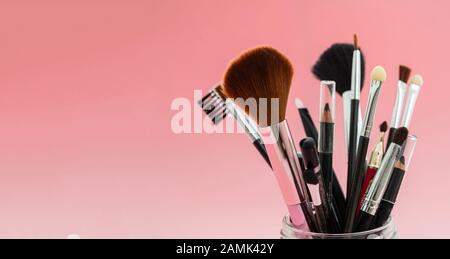 Make up brushes set against red background, top view. Professional tools for make up and art, beauty salon, cosmetics concept Stock Photo