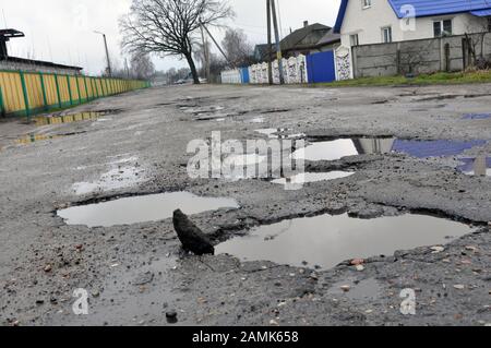 Poor road conditions. Holes in the asphalt, the risk of driving a car, poor asphalt, a dangerous road, potholes in the asphalt. Stock Photo