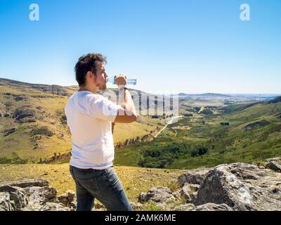 Young hiker drinking water at Cerro Bahía Blanca, Sierra de la Ventana, Buenos Aires, Argentina. Stock Photo