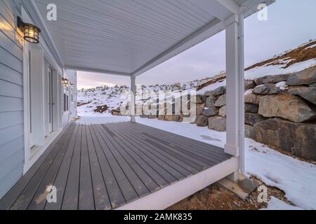 Covered wooden exterior patio facing a stone wall Stock Photo