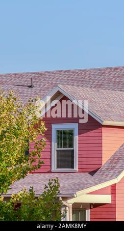 Vertical Colourful red timber clad house in green trees Stock Photo