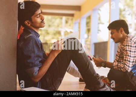 Young man fell asleep while reading at college corridor during exam - University student sleeping at campus due to lack of interest, tired or sick. Stock Photo