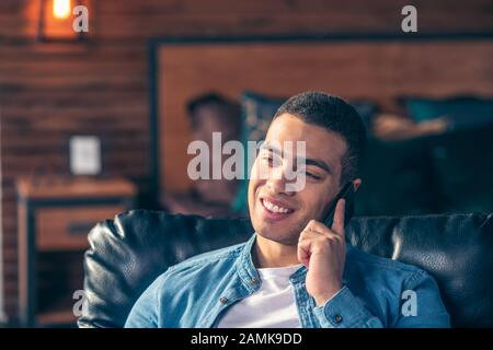 Handsome guy talking on a smartphone while at home. Stock Photo
