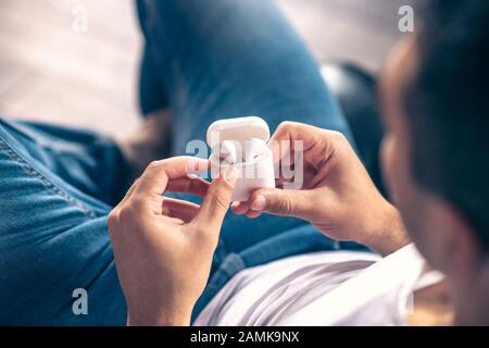 Wireless white headphones in the hands of a guy. Stock Photo