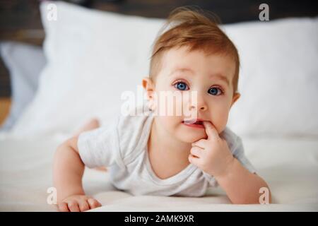 Portrait of confused baby lying on the bed Stock Photo