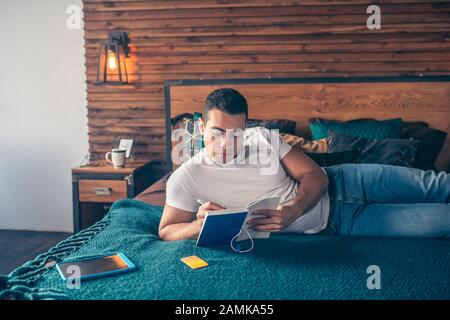 Young serious guy studying at home on the weekend. Stock Photo