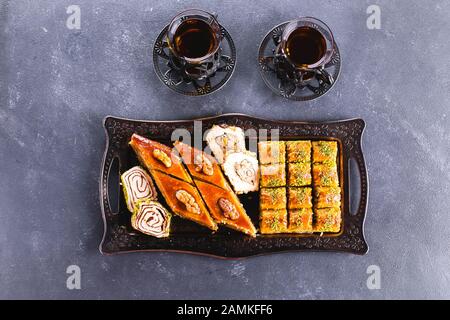 Baklava. Ramadan Dessert. Assortment of Arabic dessert with nuts and honey, cups of tea on a concrete table. Top view, copy space Stock Photo