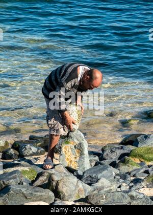 Balanced rock artist creating balanced stone sculptures our of beach pebbles on St Ives, Cornwall, England, UK Stock Photo