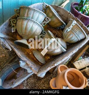 Old wooden wheelbarrow full of ornate decorative ceramic urns for sale in garden centre, England, UK Stock Photo