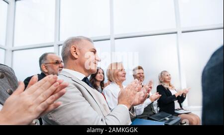 side view. smiling business seminar listeners applauding together. Stock Photo
