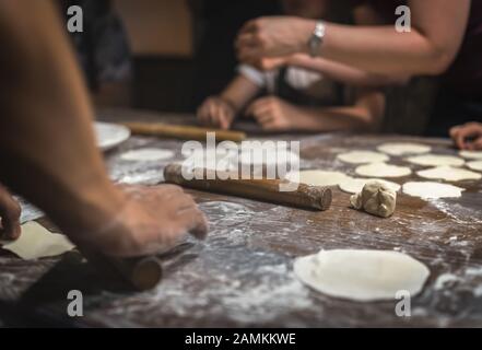 Wooden rolling pin and portioned flat dough which will be used for the making of traditional chinese dumplings during cooking class in a travellers ho Stock Photo